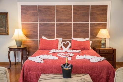 a bedroom with a bed with a red bedspread and two slippers at Pousada Quinta dos Pássaros Itaipava in Itaipava