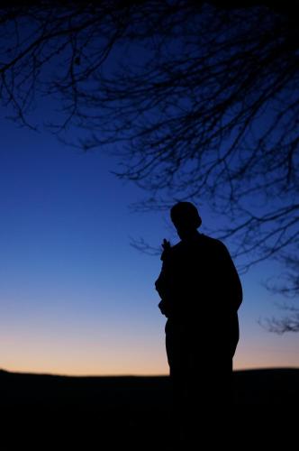 a silhouette of a person standing in front of a sunset at Teschemakers Resort in Oamaru