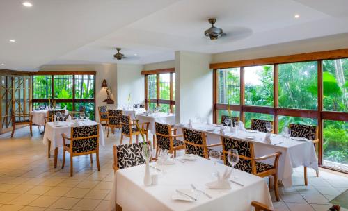 a restaurant with white tables and chairs and windows at Airways Hotel in Port Moresby