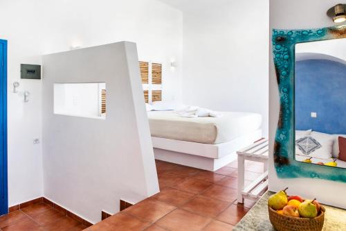 a bedroom with a bed and a bowl of fruit in a mirror at Aegeo Hotel in Chora Folegandros