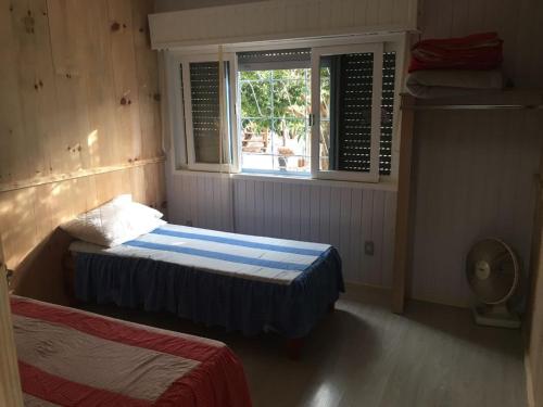 Habitación pequeña con 2 camas y ventana en Apartamento Terreo em Caxias do Sul, en Caxias do Sul