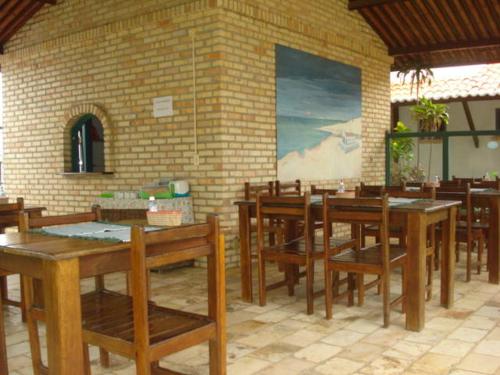 un restaurante con mesas y sillas de madera y una pared de ladrillo en Pousada 7 Mares, en Canoa Quebrada