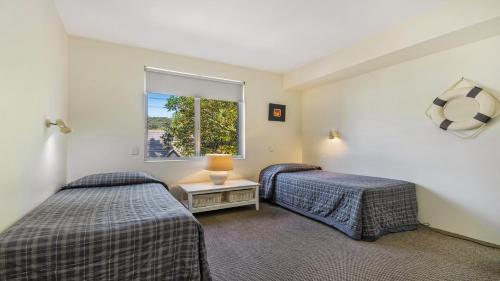 two beds in a room with a window at Park Cove Apartments in Noosa Heads