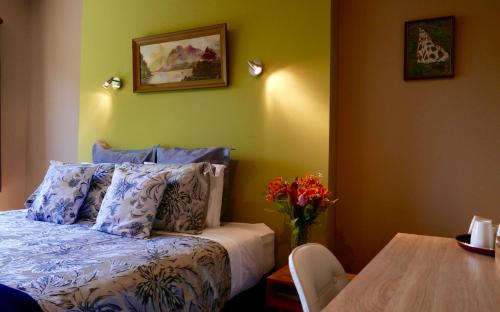 Un dormitorio con una cama y una mesa con un jarrón de flores en The Shan's Lodge en Queenstown