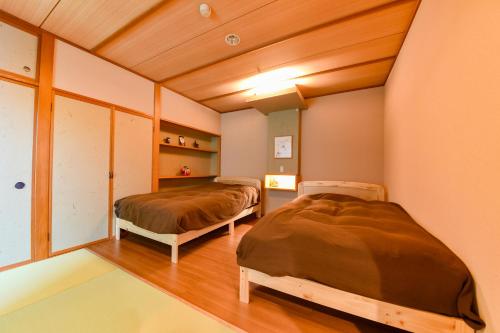 two beds in a room with wooden ceilings at Kokuya in Shibukawa