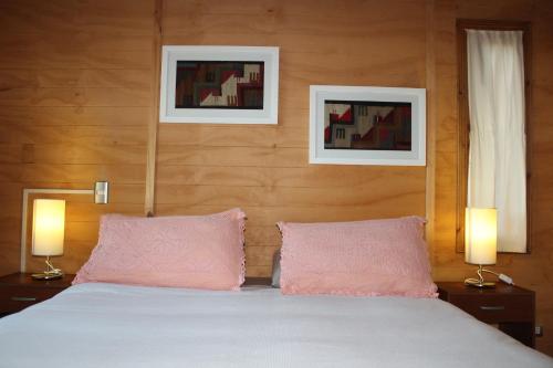 a bedroom with a bed with two pink pillows at Cabañas Mas Ke Miel in Lago Ranco