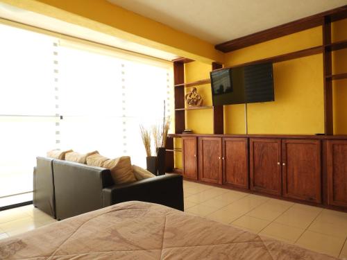 a bedroom with a couch and a television in a room at La Lotería Panoramic House & Rooftop by Lunian in Guanajuato