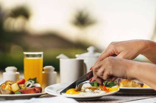 a person sitting at a table with a plate of food at Movenpick Hotel & Convention Centre KLIA in Sepang