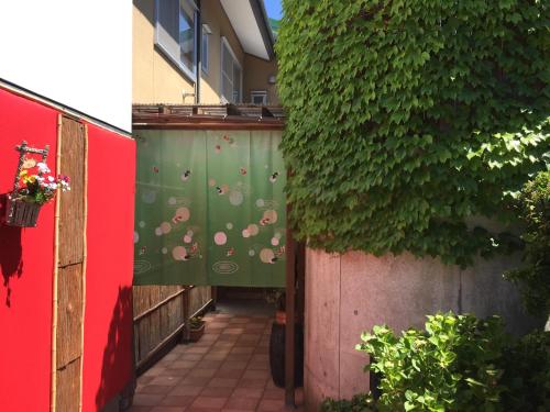 a hallway with a green wall with umbrellas on it at Daymaruya Ryokan in Yamanouchi