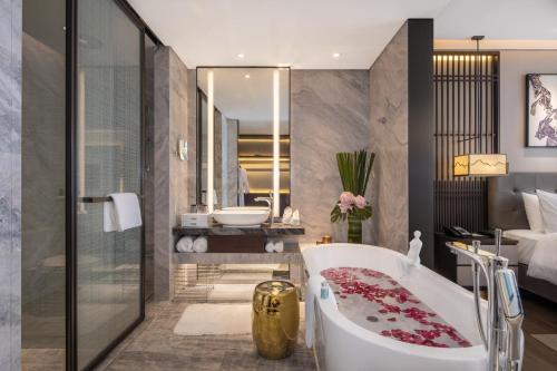 a bathroom with a bath tub and a bedroom at LiuZhou Imperial Dragon Bay Purejoy Hotel in Liuzhou