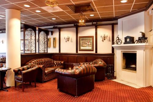 a waiting room with leather furniture and a fireplace at Chesterfield Hotel in Trondheim