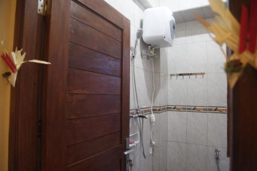 ein Badezimmer mit einer Holztür und einer Dusche in der Unterkunft Baruna Guest House in Ubud