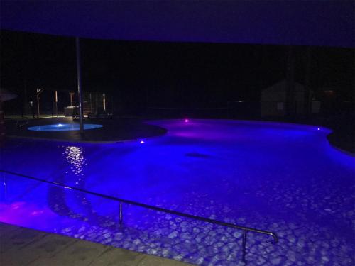 a swimming pool lit up at night with purple lights at Moruya Holiday Park in Moruya