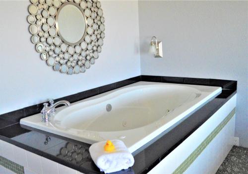 a bath tub in a bathroom with a mirror at Beachfront Manor Hotel in Lincoln City