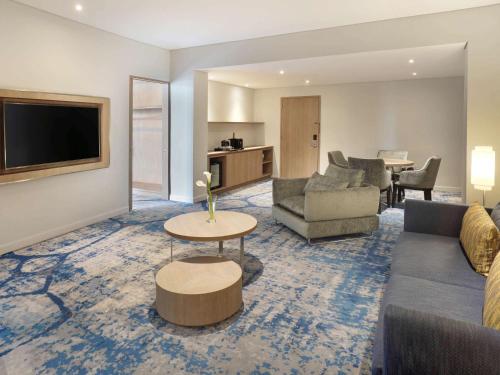 a living room with a couch and a tv at Novotel Jakarta Mangga Dua Square in Jakarta