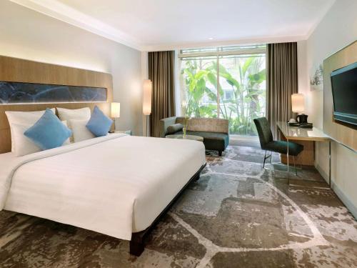 a bedroom with a large white bed and a desk at Novotel Jakarta Mangga Dua Square in Jakarta