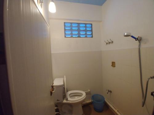 a small bathroom with a toilet and a window at Prasuri Guest House in Bangkok