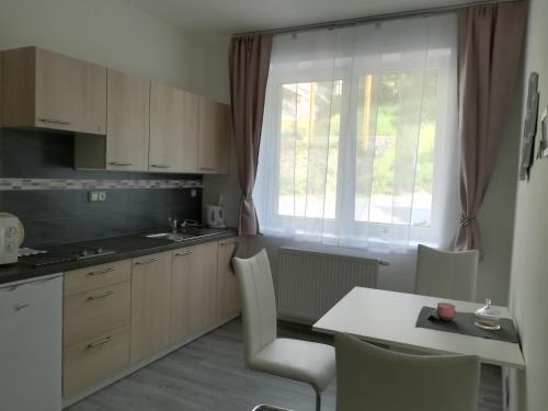 eine Küche mit einem Tisch und Stühlen sowie einem Fenster in der Unterkunft Apartmán na výsluní in Luhačovice
