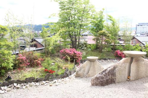 a garden with two vases sitting on a rock at Honjin Hiranoya Kachoan in Takayama