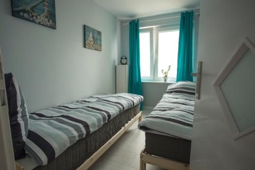 グディニャにあるWaksaの青いカーテンと窓が備わる客室で、ベッド2台が備わります。