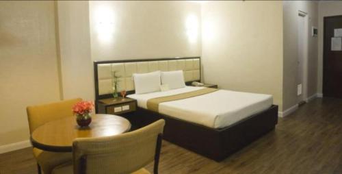 a hotel room with a bed and a table and a chair at Rothman Hotel in Manila