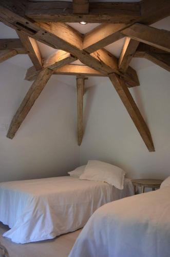 deux lits dans une chambre avec plafonds en bois dans l'établissement Le Pigeonnier de Château Picon, à Eynesse