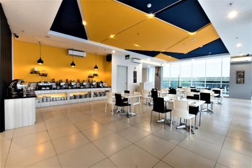 a restaurant with white tables and chairs and yellow walls at Hotel 88 Bekasi By WH in Bekasi