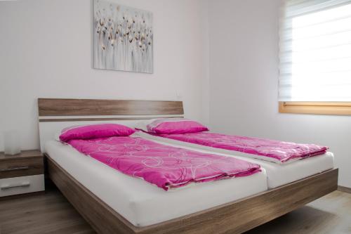 una cama con almohadas rosas en una habitación en Apartma Fani, en Podbela