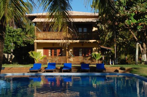 a pool with chairs and a house in the background at Pousada Praia das Ondas - Pé na areia in Itacimirim