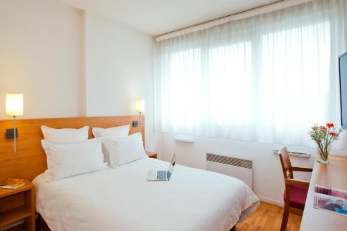 a bedroom with a large white bed and a window at Séjours & Affaires Lyon Saint-Nicolas in Lyon