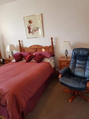 a bedroom with a bed and a blue chair at Room @ Jasmine Cottage in Bathgate