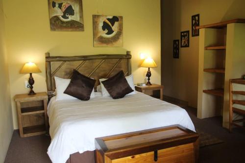 a bedroom with a large white bed with two lamps at Majuba Guest Lodge in Volksrust