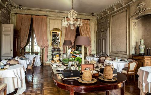 uma sala de jantar com mesas e cadeiras e um lustre em Château Des Briottieres em Champigné