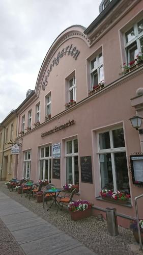 a pink building with tables and chairs in front of it at Restaurant Rosengarten in Neuruppin