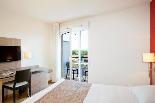 ein Hotelzimmer mit einem Bett, einem Schreibtisch und einem Tisch in der Unterkunft Séjours & Affaires Genève Gex Les Rives Du Léman in Gex