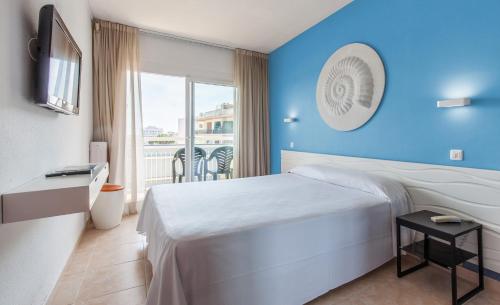 Cette chambre comprend un lit et une grande fenêtre. dans l'établissement BLUESEA Montevista Hawai, à Lloret de Mar