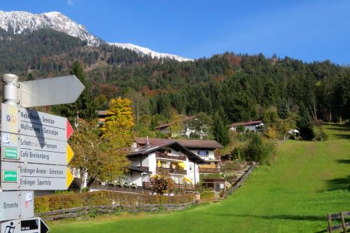 a sign in front of a house in the mountains at Ferienwohnungen Lind in Oberstdorf