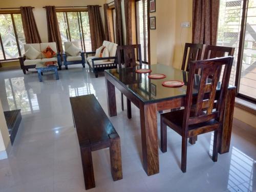 comedor con mesa de madera y sillas en Jeevan Geet, en Alibaug
