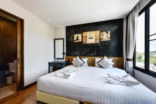 a bedroom with a white bed with a black wall at Casa Bella Phuket in Chalong 