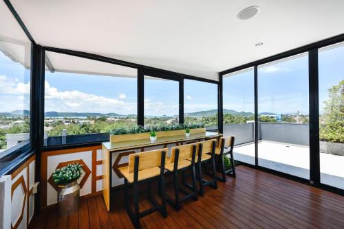 a room with a table and chairs and large windows at Casa Bella Phuket in Chalong 
