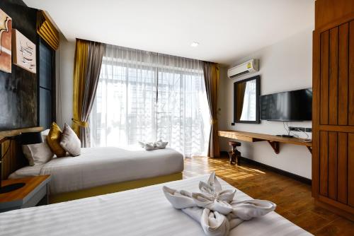 a hotel room with two beds and a window at Casa Bella Phuket in Chalong 