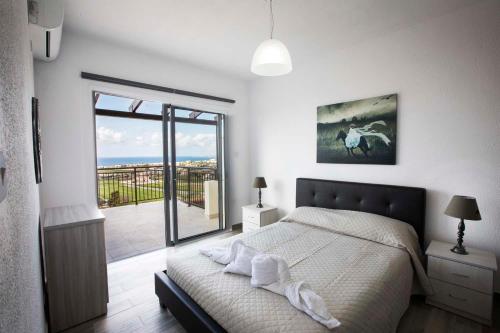 a white bedroom with a bed and a large window at Diamond Townhouse 17 in Paphos