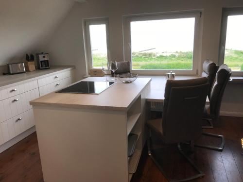 a kitchen with a island with chairs and two windows at Ferienwohnung Fritzi in Glowe