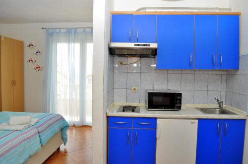 a kitchen with blue cabinets and a sink and a bed at Apartments Ivica in Makarska