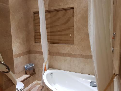a bathroom with a tub and a toilet and a sink at Bubez Guesthouse in Barberton