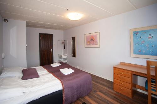 a bedroom with a bed and a wooden dresser at Strand Fjordmotel in Ulvik