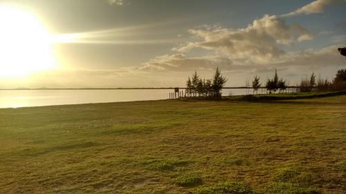 a field of grass with the sun in the sky at Villaggio dos Ventos in Arraial do Cabo