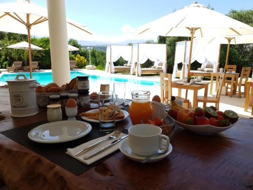 einen Tisch mit einem Frühstück mit Obst und Saft neben einem Pool in der Unterkunft Villa Torrella in Mezzavia