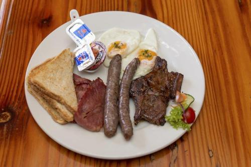 a white plate of food with sausage and toast at Augrabies Falls Lodge & Camp in Augrabies