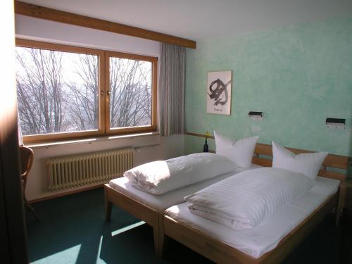 Schlafzimmer mit einem Bett mit weißer Bettwäsche und einem Fenster in der Unterkunft Humboldt-Haus in Achberg